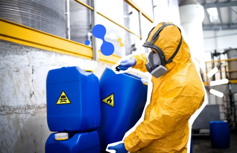 Travailleur en combinaison de protection manipulant des bidons de produits chimiques dans un environnement industriel pendant une formation sur les risques chimiques.