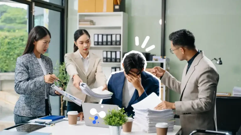 Un employé débordé au bureau se tient la tête entre les mains pendant que trois collègues lui tendent des dossiers, illustrant la surcharge de travail et le stress professionnel.