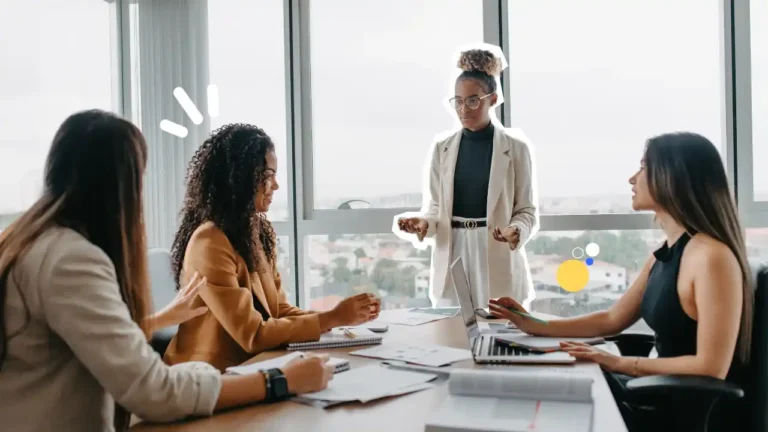 Une formatrice anime une réunion professionnelle avec trois participantes autour d’une table, illustrant la communication, la collaboration et le leadership en entreprise.