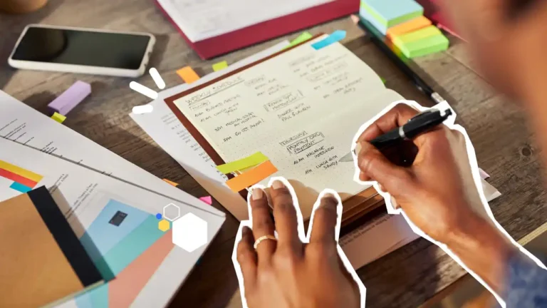 Une personne organise son planning hebdomadaire dans un carnet, entourée de documents, de post-it et d’un smartphone, illustrant la gestion du temps et la planification au travail.