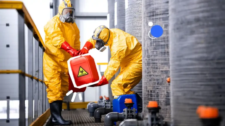 Deux opérateurs en combinaison de protection manipulent un bidon de produit chimique dangereux dans une zone industrielle, illustrant la prévention des risques chimiques en entreprise.
