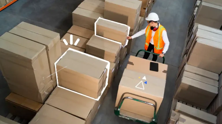 Agent logistique en gilet haute visibilité manipulant des cartons sur un transpalette dans un entrepôt, illustrant les bonnes pratiques de chargement et déchargement en sécurité.